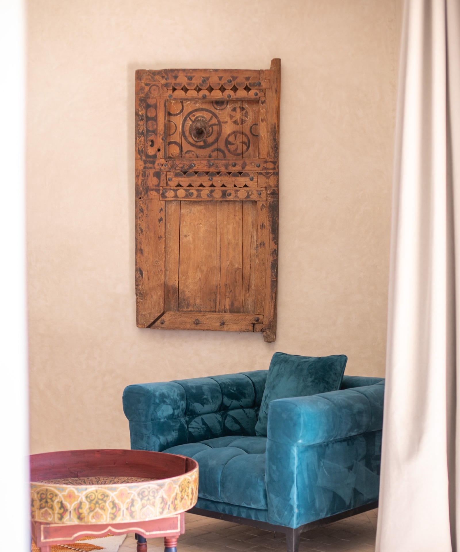 An antique carved wooden panel above a velvet sofa