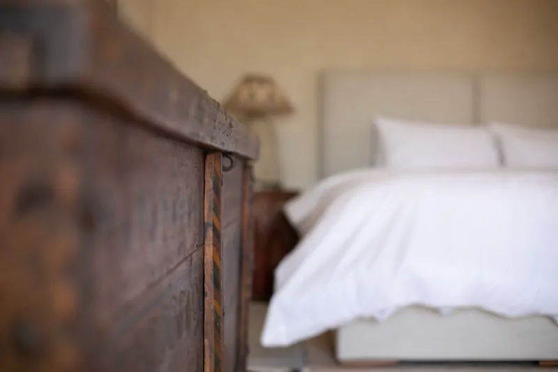 Suite Quatre : coffre ancien en bois au pied du lit